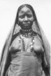 Polopostava ženy s obnaženými prsy a rouškou přes hlavu a šňůrami korálů na krku, kmen Hamayd