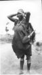 Žena v přehozu z látky, s pletenou kabelou, v níž nese lahvici z tykve, Kikujové