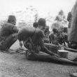 Sedící žena s dítětem na zádech zakrytým mísou z tykve, Kikujové