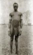 Muž s náramky a nápažníky z drátu, pas a břicho omotané šňůrou či drátem,  Kamčuru (Ačoli)