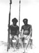 Dva sedící muži s kopími