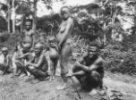 Muži sedící v dřepu, stojící žena a děti, Bambuti