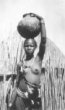 Dívka v přehozu z kůže nese na hlavě velkou kulatou nádobu, Šilukové