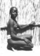 Dívka se skarifikací na čele sedící v kleku u ohrady z rohože, Šilukové