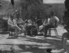 B.Machulka ve společnosti dalších pěti mužů sedí na židlích v zahradě