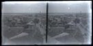 Dvojsnímek. Výškový pohled na město přes střechy domů, zprava ulice, v dáli věžička