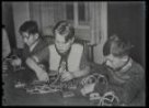 Fotografie, tři chlapci sedící za stolem zkoušejí jednoduchou elektrotechniku